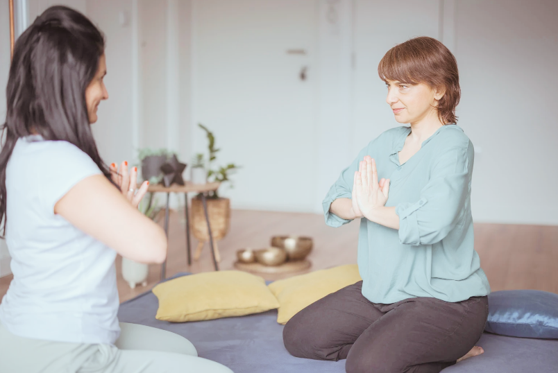 two people facing each other sitting in prayer pose