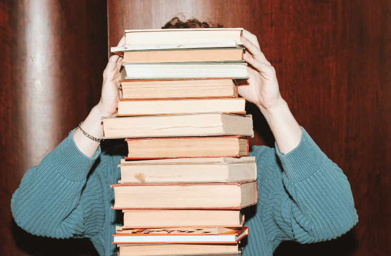 person hidden behind a stack of books