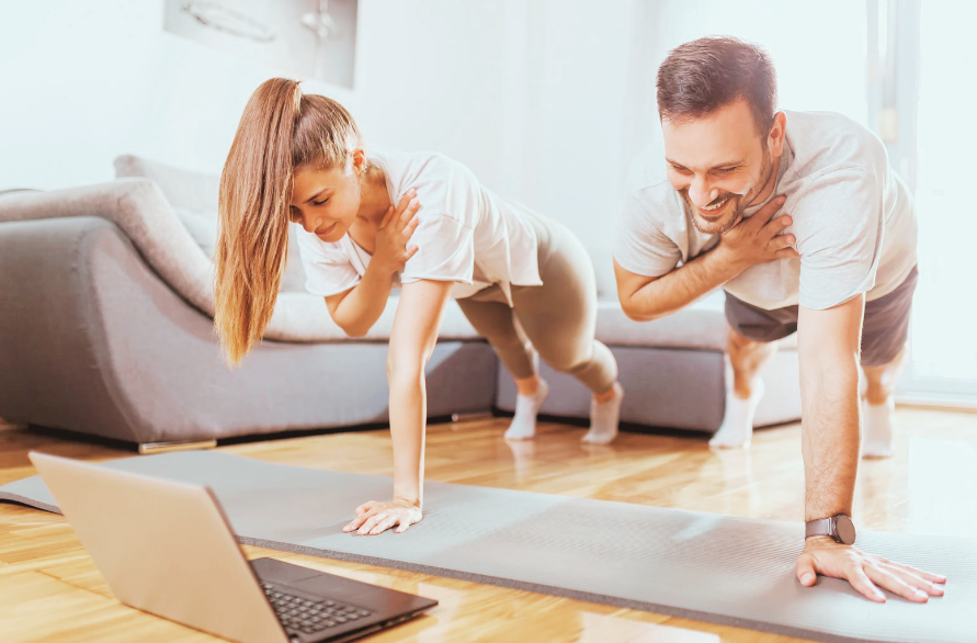 two people doing yoga in front of a laptop