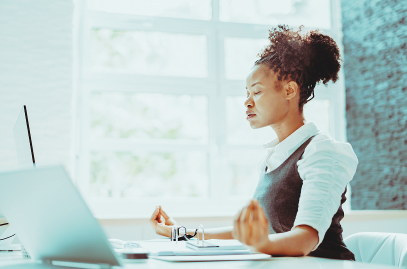 person sitting in meditation pose in front of their laptop