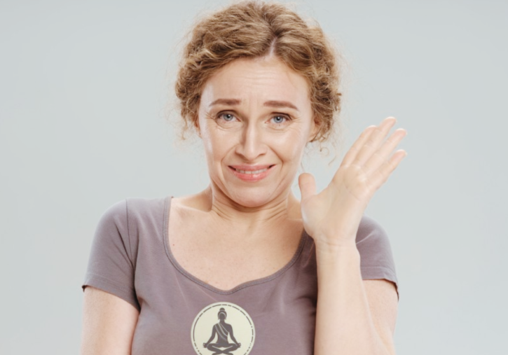 person in yoga tee shyly raising hand