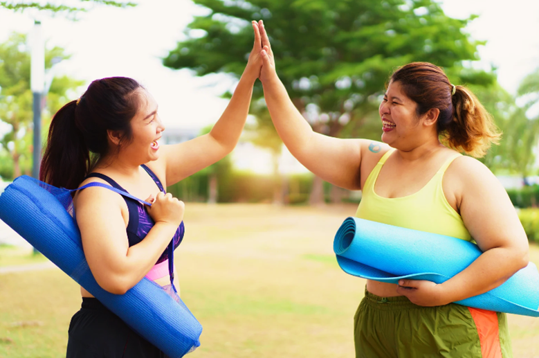 two people holding yoga mats and high fiving
