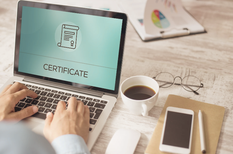 laptop showing certificate with coffee, glasses, phone and mouse on table