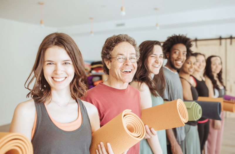 group of smiling yogis holding yoga mats