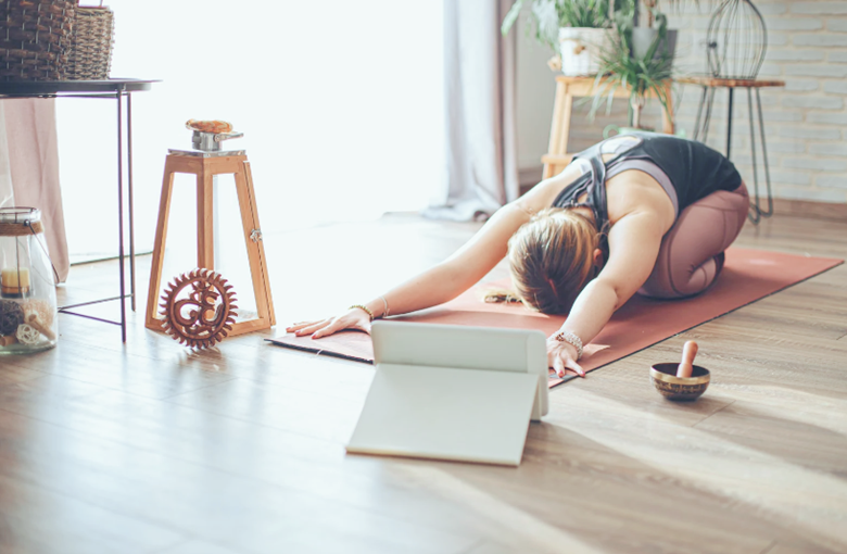 person doing yoga in front of a laptop